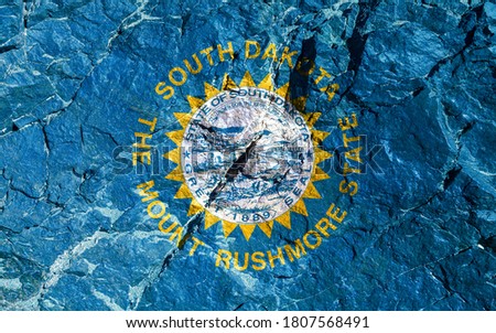 The national flag of the United States of South Dakota, stamped on a white or azure navy blue background, framed in gold with a stylized jagged sun. Rock graffiti of climbers during the ascent.