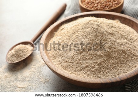 Buckwheat flour in wooden bowl on table, closeup