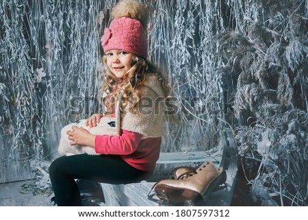 little girl holding a rabbit in her arms in winter on a frozen lake on horse trails