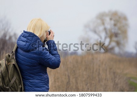 girl photographer with a camera in autumn in nature. Travel and photography. Young woman photographer, blogger shoots a beautiful landscape. back view