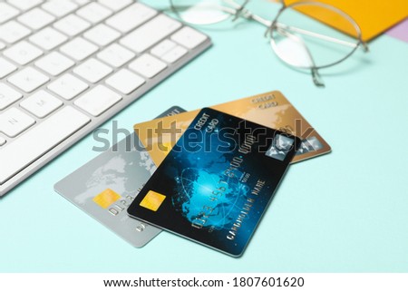 Credit cards near computer keyboard on light blue background