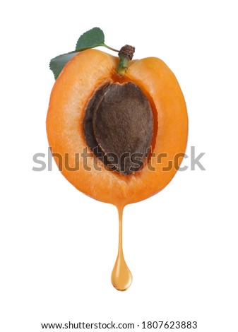 Apricot kernel oil dripping from fresh fruit half on white background Royalty-Free Stock Photo #1807623883