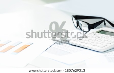 Finance and business concept. White calculator and percentage sign on financial graphs on office desk, paperwork binder, glasses. Accounting budgeting or market analysis. Web banner with copy space