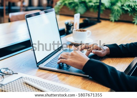 Unrecognizable woman using laptop at wooden desk stock photo