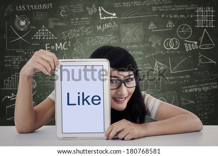Asian female student showing like on touch pad at classroom