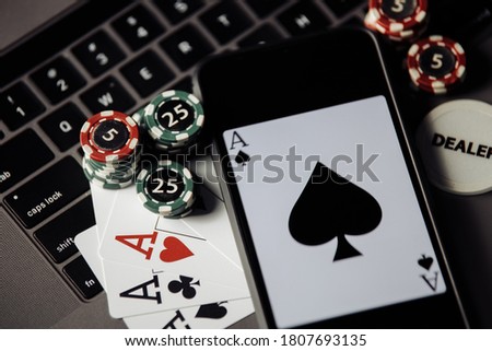 Stack of gambling chips, smartphone and playing cards on a laptop keaboard. Close-up. Online casino concept