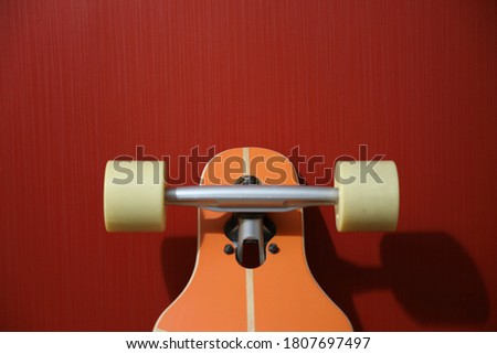 orange longboard with beige wheels on a red background