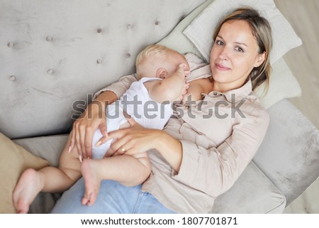 From above fiew shot of modern young mother nursing her little baby son on sofa