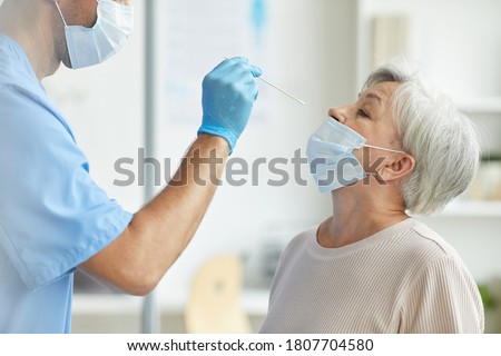 Side view shot of professional medical worker taking nasal swab sample for infection using test stick