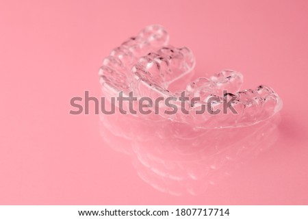 Two Invisible dental teeth aligners on the pink background. Orthodontic temporary removable braces for fixing teeth after alignment. Therapy after brackets.  Royalty-Free Stock Photo #1807717714