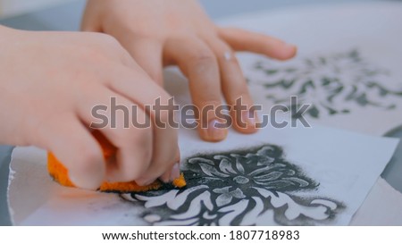 Stencil painting: close up shot of woman hands painting wooden circle. Paint, handmade and crafting work concept Royalty-Free Stock Photo #1807718983