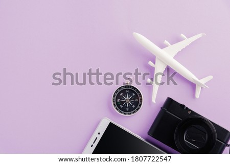 World Tourism Day, Top view of minimal model plane, airplane, starfish, alarm clock, compass, camera and smartphone, studio shot isolated on a purple background, accessory flight holiday concept