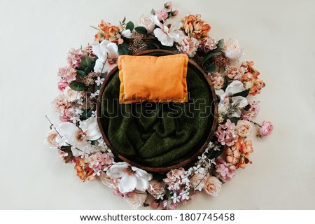 Newborn photography background - floral wreath on white background with wooden bowl and green knitted center. Newborn magnolia spring backdrop.