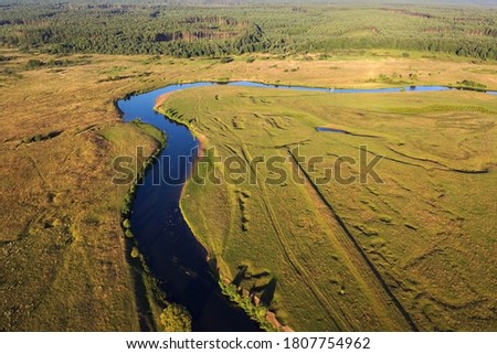 Aerial view of winding river and forest. Summer landscape, top view. A green valley with a winding riverbed