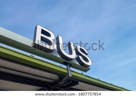 big white physical bus sign type all capital letters at a bus stop