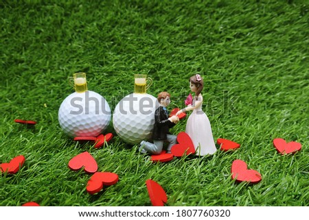 Golf wedding with bride and groom and golf ball on green grass