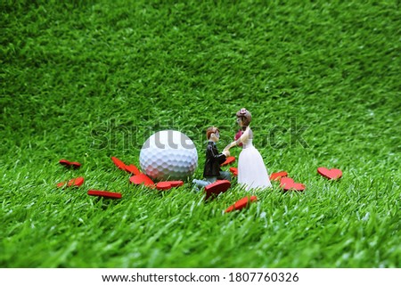 Golf wedding with bride and groom and golf ball on green grass
