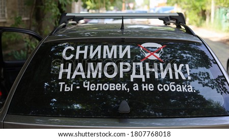 The inscription on the glass of the car in Russian - Take off your muzzle, you are a man, not a dog. An open protest against the state's restrictive measures during a lockdown.