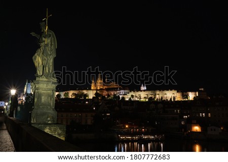 
statue on Charles Bridge and in the background the Church of St. Vitus and Prague Castle at night