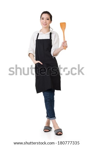 Young Asian housewife hold a spatula in apron, full portrait isolated on white background.