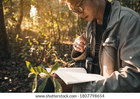 Botanists are taking note of the plants found in the tropical forests. Biologist researching in the forest. Botanist studying a newly flowering plant species. Royalty-Free Stock Photo #1807798654