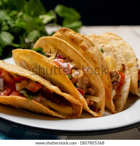 Traditional mexican hard-shell tacos with meat and fresh sauce on white background