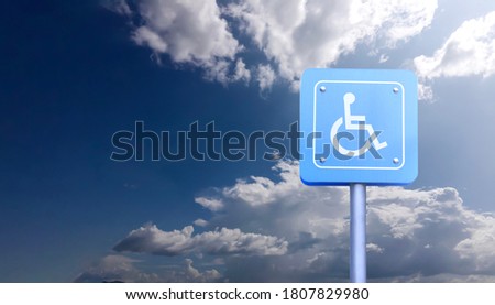 The wheelchair sign on pole with blue sky background.
