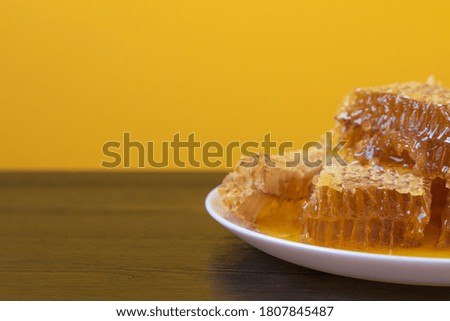 Honeycombs in white plate on the wooden table. Natural organic bee product. Healthy lifestyle. Copy space for your text. Close-up photo.