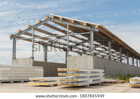 Metal frame of the building with a sandwich panel of insulation on the wall. Construction of a new industrial building. Modern Insulation of the walls of the building panels of insulation. Royalty-Free Stock Photo #1807845949