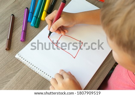 A small child draws a house with markers in the album. Step-by-step instructions