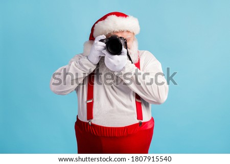 Portrait of his he nice attractive white-haired Santa holding in hands professional camera shooting taking making photo cadre focus event isolated bright vivid shine vibrant blue color background