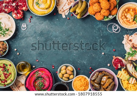 Traditional Middle Eastern assorted meze: hummus, pita, olives, pistachios, dolma, falafel balls, pickles, babaganush, vegetables, pomegranate, eggplants. Top view. Banner. Copy space. Arab meal. Royalty-Free Stock Photo #1807918555