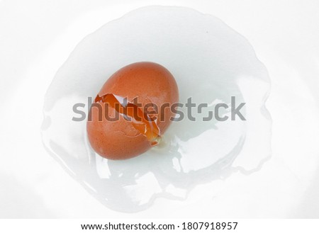 Broken eggs fall on the floor, white scene on a plate