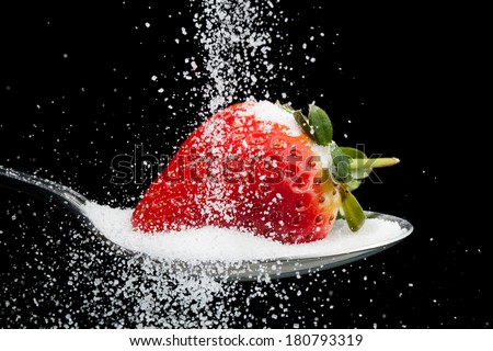 Sugar pouring over a strawberry on a spoon with a black background Royalty-Free Stock Photo #180793319