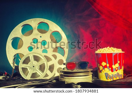 Old film reels, popcorn and 3d glasses on the table. Focus on glasses. Multicolored background. Evolution Film Media