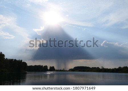 Rainy cloud with sun over lake