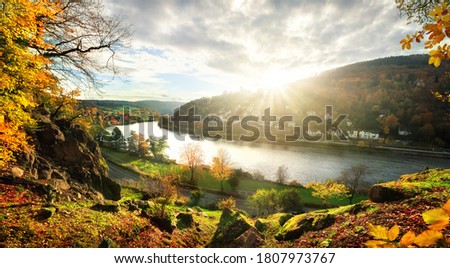 View onto the Neckar river and idyllic landscape near Heidelberg, Germany, as the sun is about to set behind a hill on a colorful autumn day