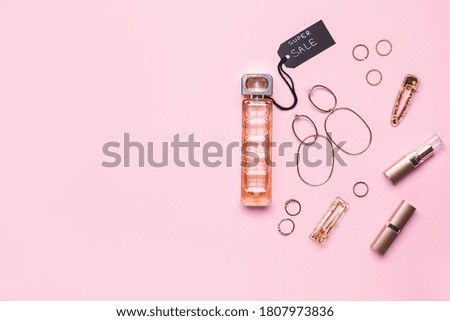 Bottle of perfume for sale with makeup cosmetics and accessories on color background