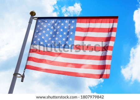 Large American flag waving in the wind with a blue sky background
