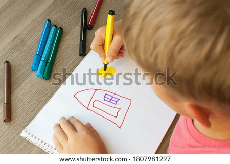 A small child draws a house with markers in the album. Step-by-step instructions.