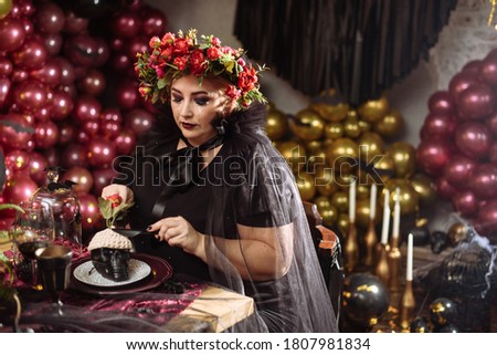 An adult woman in a witch costume eats brains from a skull. Scary and glamorous Halloween pictures
