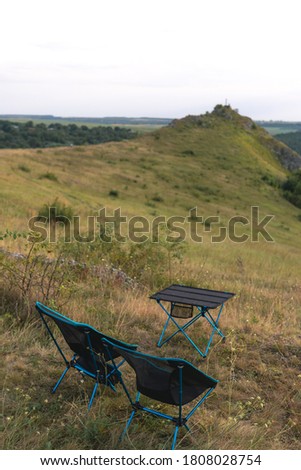 lightweight and compact equipment. Folding chairs and a table stand on the banks of the river. Tourism equipment in nature in a natural environment. Equipped holiday camp. no bodies. vertical photo