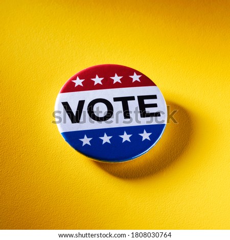 a vote badge, with the colors and the stars of the United States, on a textured yellow background Royalty-Free Stock Photo #1808030764