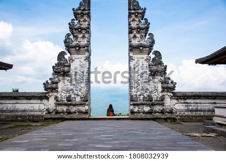 An European tourists taking pictures in Hindu temple heaven's gate wearing Sarong with blue background sky in Bali, Indonesia