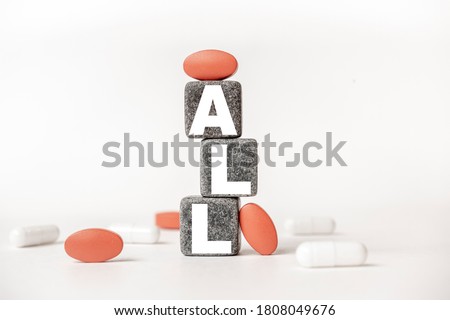 a group of white and red pills and cubes with the word ALL Acute lymphoblastic leukemia on them, white background. Concept carehealth, treatment, therapy.