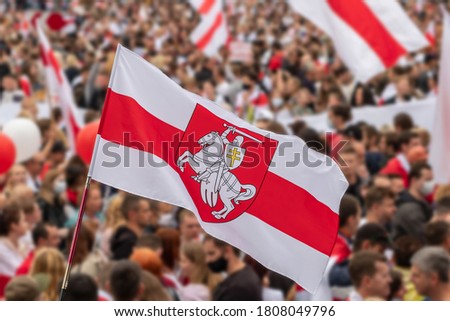 National white red white flag of Belarus with historic belarusian coat of arms Pahonia. Blurred crowd of people protesting after 2020 presidential elections. Belarus White-red-white flag Royalty-Free Stock Photo #1808049796