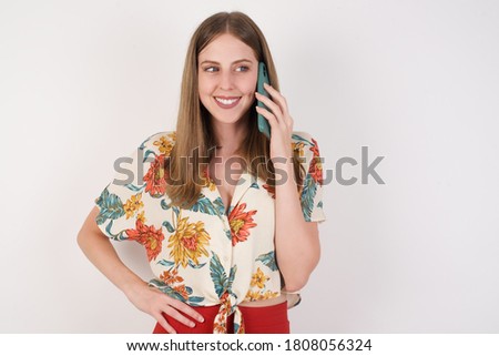 Lifestyle Concept - Portrait of beautiful Caucasian joyful woman talking on mobile phone with friend. White pastel studio background. Copy Space.