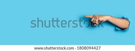 Hand points to something on a blue background. Gesture look at this, pay attention Royalty-Free Stock Photo #1808094427