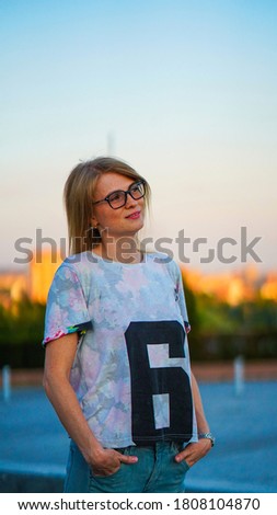 Young smiling woman with number six on shirt holding hands in pockets