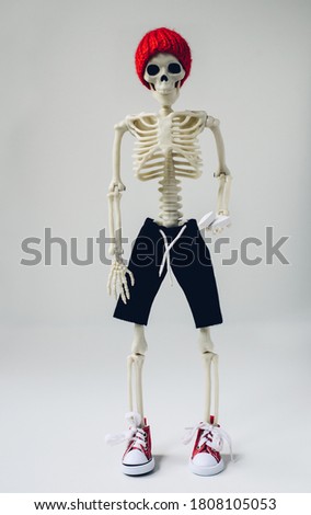 A skeleton in a hat and sneakers holds pills in his hands. Anatomy.